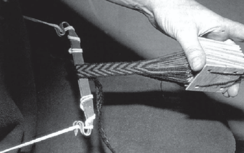 A photograph of a braid being woven with tablets and a clasp.