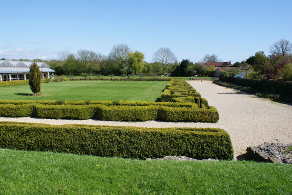 A large lawned area surrounded by broad, well kept, low level, topairy hedging and broad gravelled paths - There are also other styles of garden on each side