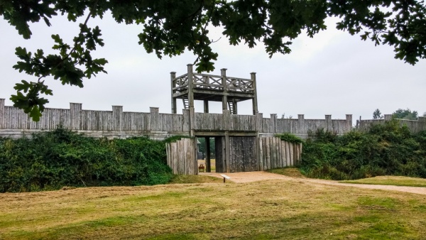 A photo showing a gatehouse structure with extensive wooden defensive walls either side