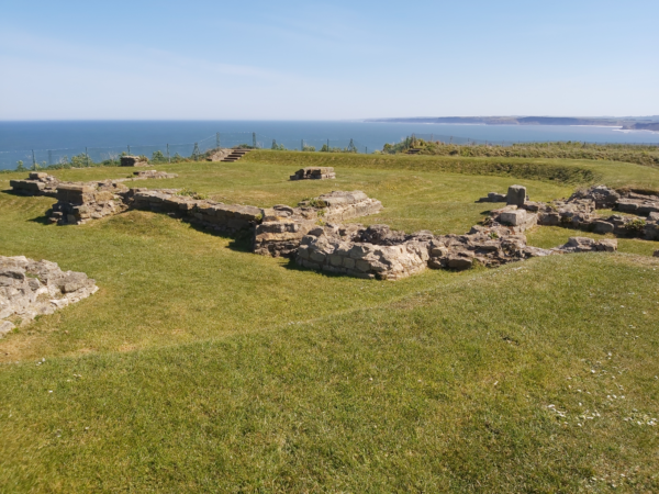 A colour photo showing a well maintained ruin from a cliff top view - there is a range of walls and structures that remain from a fortlet close to Scarborough Castle - there is also a bank that surrounds most of this area