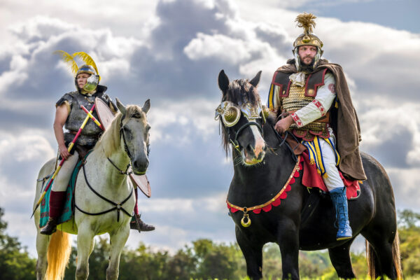 A colour photo showing two mounted cavalry riders one on a white horse, the other on a black horse stand ready for action