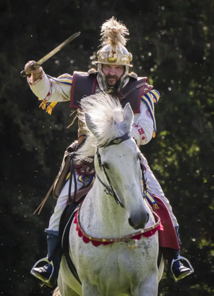 A colour photo of a mounted Roman cavalry rider charging into battle holding out his gladius (sword) heigh above his shoulder