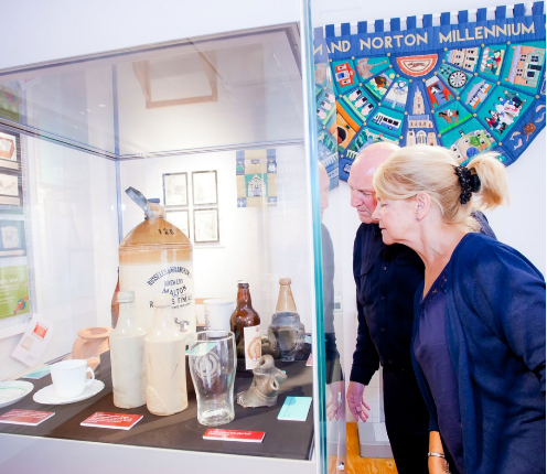 Visitors looking at museum displays in glass cases.