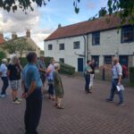 A group of men and women listen to a tour guide.