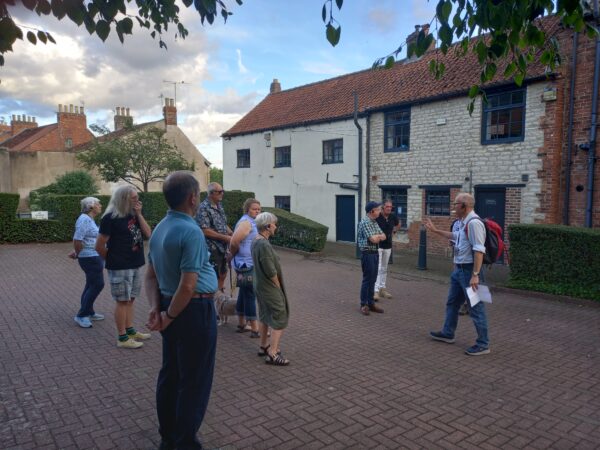 A group of men and women listen to a tour guide.