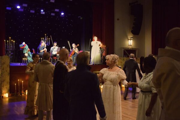 Men and women in Georgian costumer dance while a strings quartet play in the background at Malton Regency Ball.